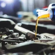 Wlewanie oleju do silnika 1.9 TDI. Płynny złoty olej z niebieskiej bańki zasila serce samochodu.