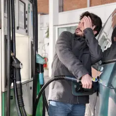 Zmartwiony mężczyzna tankuje samochód. Szuka informacji, gdzie tankować CNG, bo skończyło mu się paliwo.